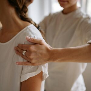 A detailed view of a physiotherapy session with hand placement on shoulder indoors.